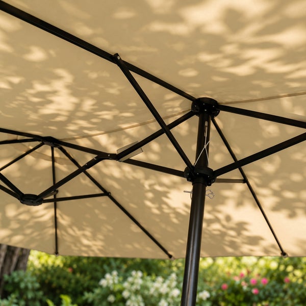 Unterseite eines Doppelsonnenschirms mit schwarzem Metallgestell und beigem Bezug im Garten.