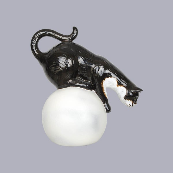 Dekofigur einer schwarz-weißen Katze auf einer weißen Kugel aus Polyresin.