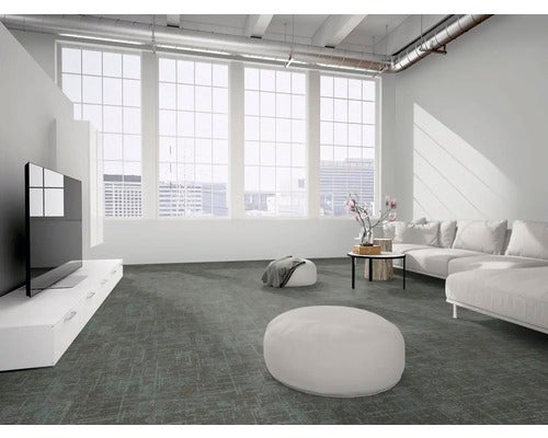 Moderner, heller Wohnraum im Loft-Stil mit großflächigem, grau gemustertem Teppichboden, weißem Sofa und großen Fenstern.