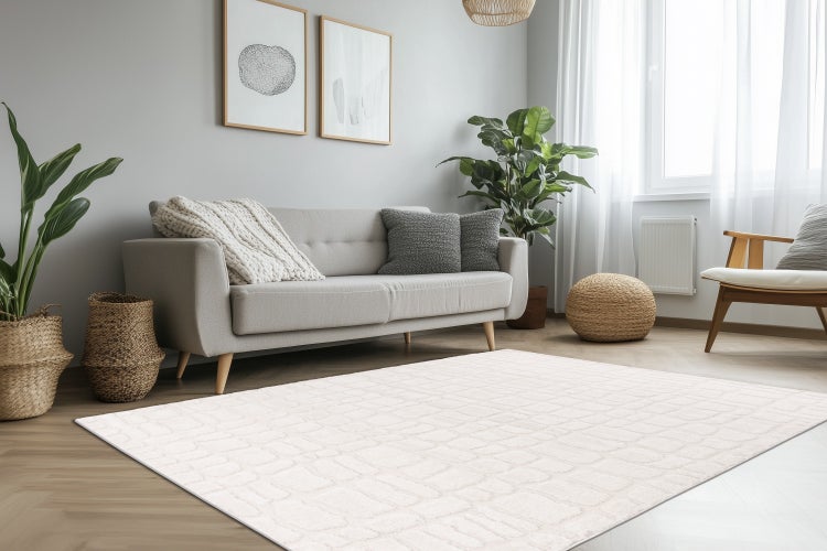 Wohnzimmer mit einem rechteckigen Teppich mit geometrischem Muster auf einem Holzfußboden, dazu ein Sofa, Sessel und Dekoration.