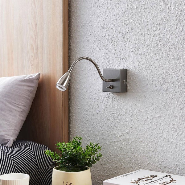 Moderne Wandleseleuchte mit flexiblem Arm aus Metall, montiert neben einem Bett an einer strukturierten Wand.