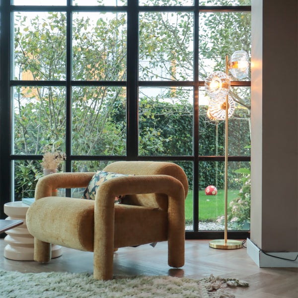 Wohnzimmer mit Sessel, Stehlampe und Blick durch ein Fenster