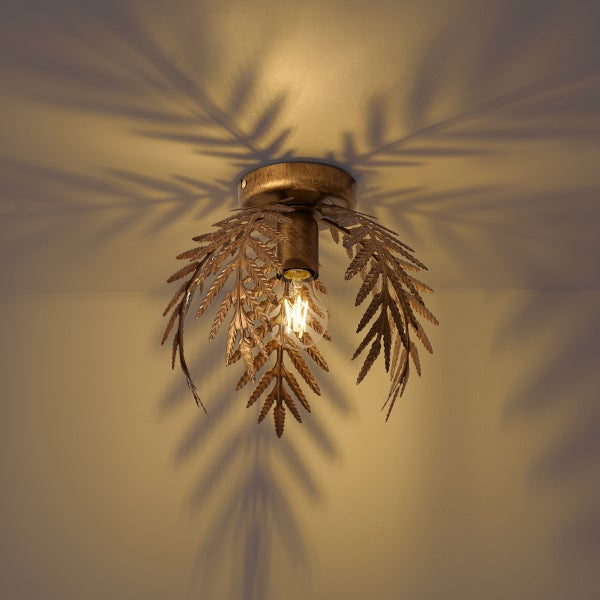 Metall-Deckenleuchte im Farn-Design in Bronze-Optik mit eingeschaltetem Leuchtmittel und Schattenwurf an der Decke.