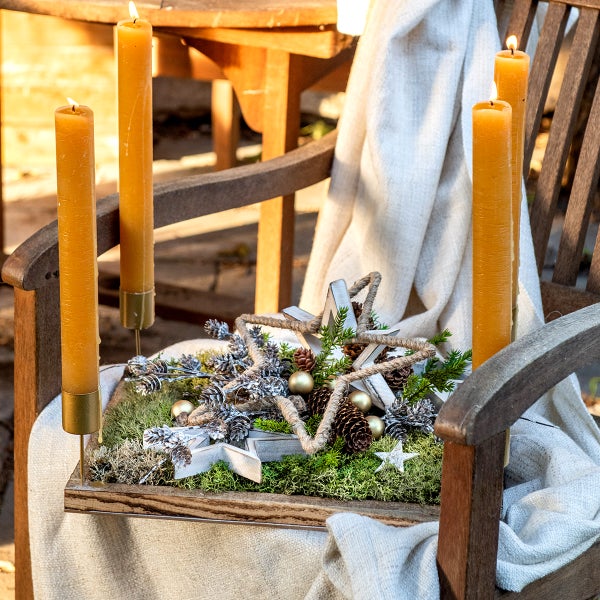 Dekoration mit Kerzen, Sternen und Tannenzapfen auf einer Holzbank