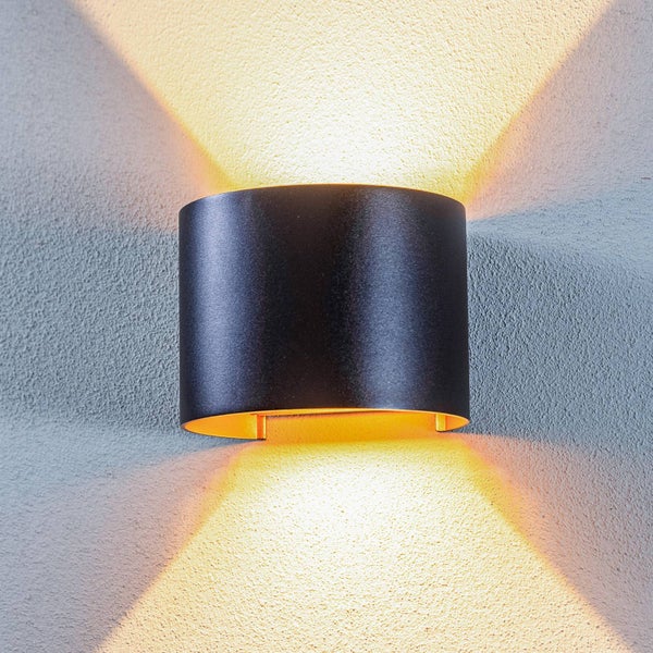 Moderne Außenwandleuchte mit Lichtaustritt nach oben und unten an einer strukturierten Wand.