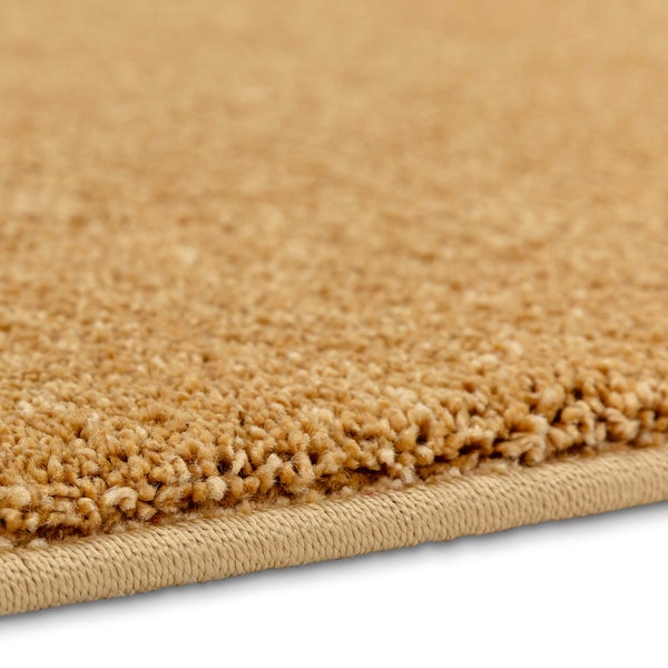 Nahaufnahme eines beigen Teppichs mit Hochflor-Struktur und geketteltem Rand.