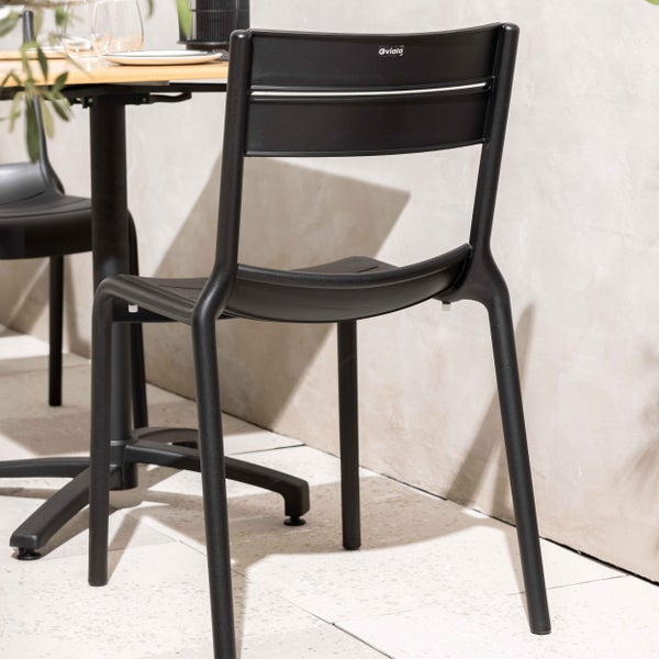 Schwarzer Gartenstuhl aus Kunststoff mit Oviala Logo an einem Esstisch auf einer hellen Terrasse.