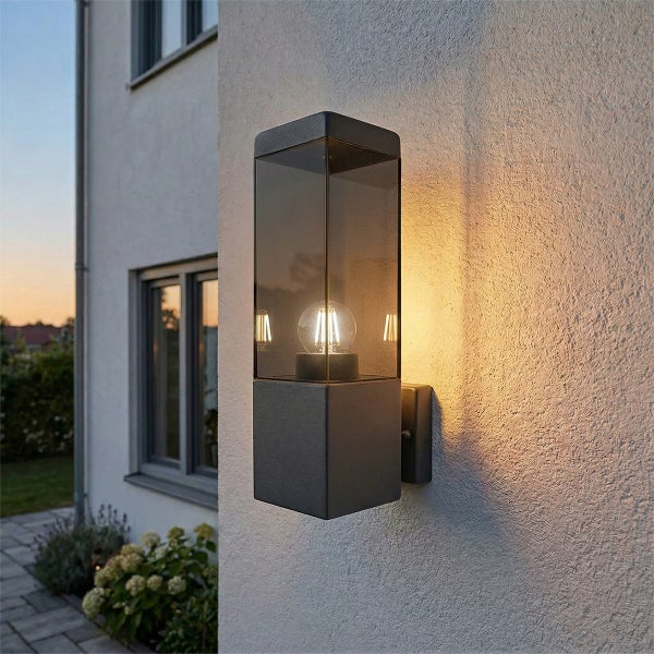 Moderne rechteckige Außenwandleuchte in Anthrazit mit klarem Glas und sichtbarem LED-Filament-Leuchtmittel montiert an einer Hauswand.