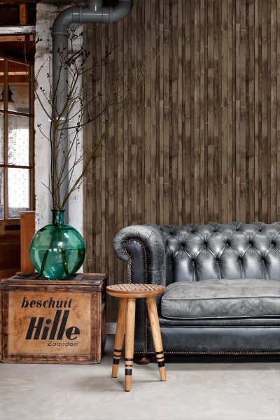 Wohnszene mit Chesterfield-Sofa, Holzhocker und Wandtapete in Holzoptik