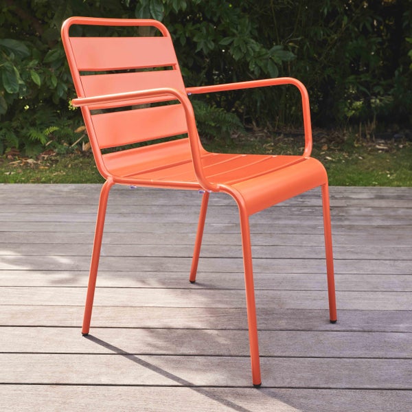 Gartenstuhl mit Armlehnen aus orangefarbenem Metall mit Lattenstruktur auf einer Holzterrasse im Garten.