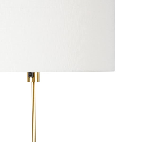 Detailansicht einer Stehlampe mit hellem Lampenschirm und goldenem Gestell