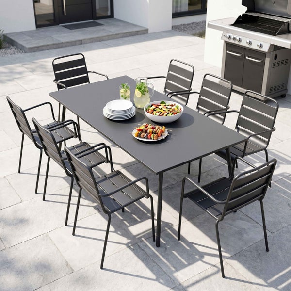 Modernes Gartenmöbel-Set mit großem rechteckigem Tisch und acht Metallstühlen mit Latten-Design auf einer geräumigen Terrasse neben einem Grill.