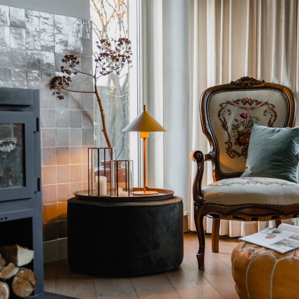 Wohnzimmer-Interieur mit Kamin, Sessel, Lampe und Dekorationen für eine gemütliche Atmosphäre