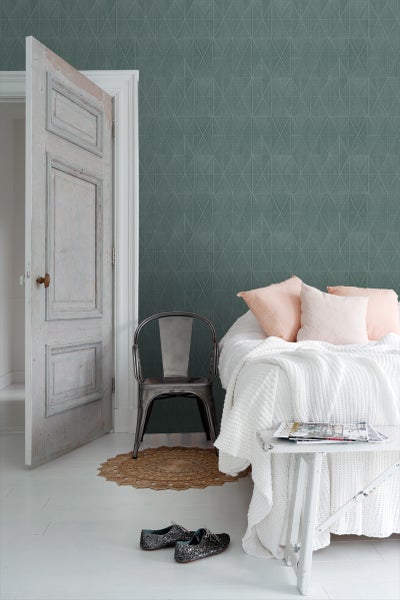 Schlafzimmer mit geometrischer Tapete, Bett, Stuhl und Tür