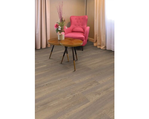 Moderner Bodenbelag in Holzoptik in einem hellen Wohnzimmer mit rosa Sessel und runden Couchtischen aus Holz.