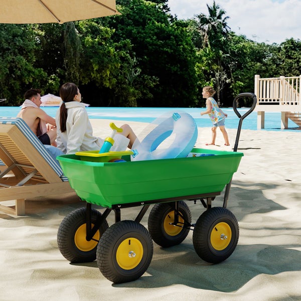 Grüner Gartenwagen mit Luftbereifung auf Sand, beladen mit Strandspielzeug. Im Hintergrund Personen am Pool.