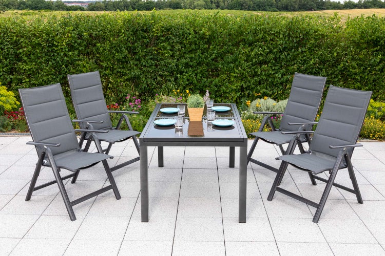 Gartenszene mit Esstisch und vier Stühlen auf einer Terrasse.