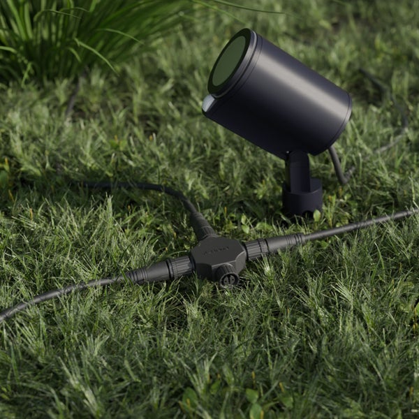 Gartenstrahler mit Bewegungsmelder und Kabelverteiler auf einer Rasenfläche.