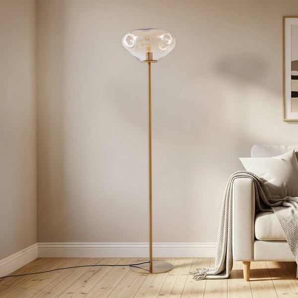 Stehlampe mit goldfarbenem Gestell und transparentem Glasschirm im Wohnzimmer
