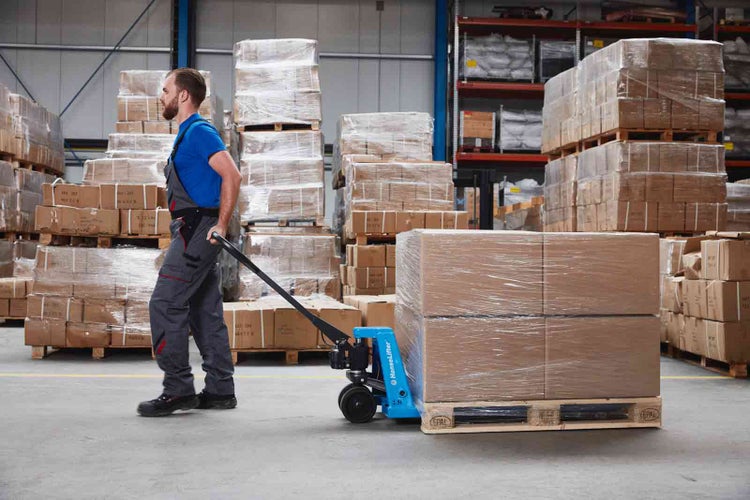 Lagermitarbeiter zieht einen beladenen HanseLifter Hubwagen mit Europalette in einem organisierten Lagerbereich.