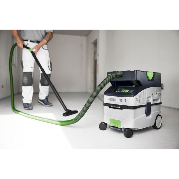 Handwerker im hellen Rohbau beim Einsatz eines Festool Absaugmobils mit Autoclean Funktion und Saugschlauch zur Bodenreinigung.