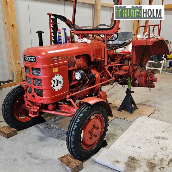 Roter Fahr D180H Oldtimer Traktor in einer Werkstatt auf einem Unterstellbock abgestützt mit Trutzholm Logo