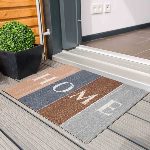Fußmatte mit der Aufschrift HOME vor einer Haustür