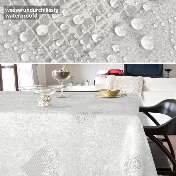 Wasserundurchlässige Tischdecke mit Blumenmuster und Herzmotiv, Detailaufnahme von Wassertropfen auf der Oberfläche.