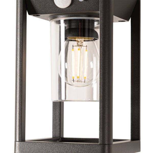 Nahaufnahme einer schwarzen Außenleuchte mit einem Glaszylinder und einem leuchtenden Filament Leuchtmittel inklusive Bewegungsmelder.