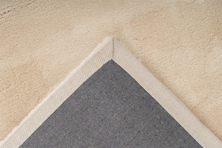 Beiger, rechteckiger Hochflor-Teppich in schlichtem Design.