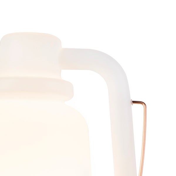 Detail einer modernen tragbaren Lampe mit mattweißem Gehäuse und kupferfarbenem Metallbügel.