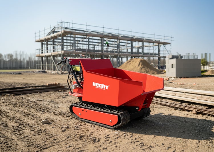 Hecht Raupendumper auf einer Baustelle vor einem Gebäude im Rohbau auf sandigem Boden.