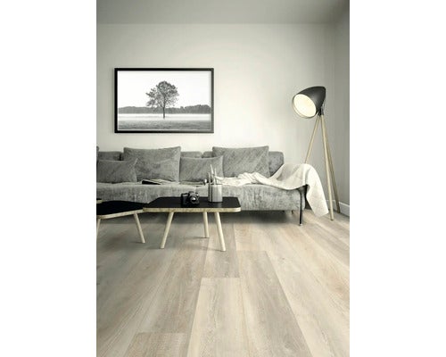 Modernes, helles Wohnzimmer mit Bodenbelag in Holzoptik, Sofa, Couchtisch, gerahmtem Wandbild und einer Stehlampe.