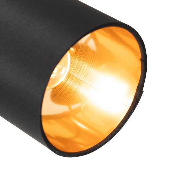 Nahaufnahme eines zylindrischen Lampenschirms mit schwarzer Stoffaußenseite und goldfarbener Innenseite.