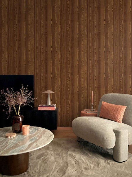 Wohnzimmer mit Vliestapete in Holzoptik mit vertikaler Maserung, kombiniert mit modernem Sessel, Marmortisch und schwarzem Sideboard.
