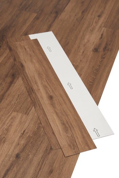 Selbstklebende Vinylplanke in Holzoptik mit Pfeilen für die Verlegerichtung auf der Rückseite.