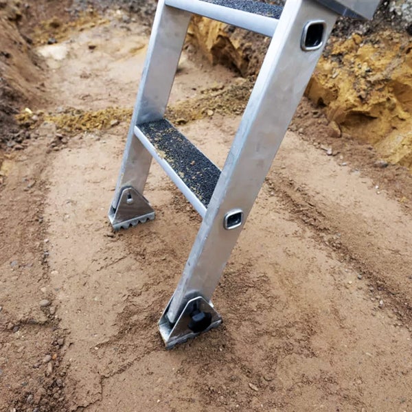 Detailaufnahme einer Aluminiumleiter auf einem Sandboden.