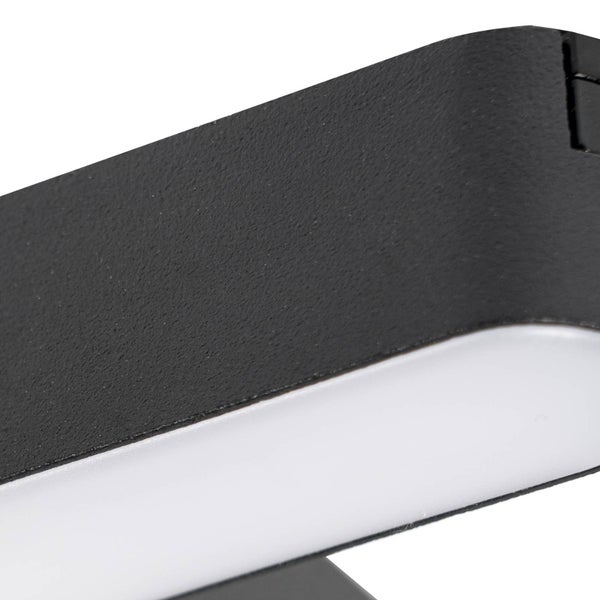 Detailaufnahme einer schwarzen Wandleuchte mit strukturierter Oberfläche und weißem Diffusor.