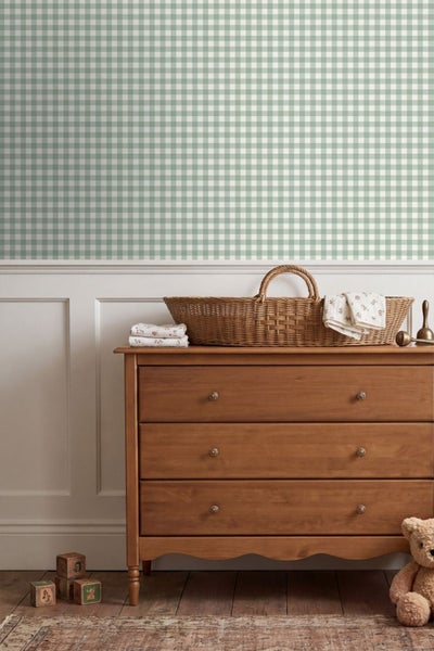 Vliestapete mit feinem Vichy-Karo über Wandvertäfelung in einem Kinderzimmer mit Holzkommode und Weidenkorb.