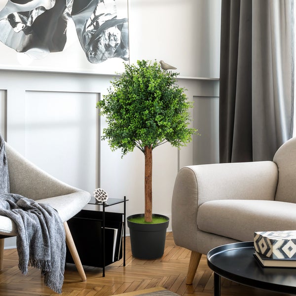 Dekoratives Zimmer mit Kunstbaum, Sesseln und Beistelltischen für eine wohnliche Atmosphäre.