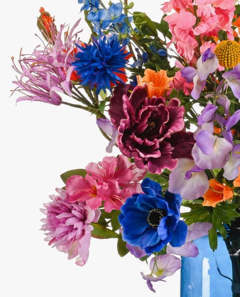 Künstlicher Blumenstrauß mit bunten Blüten wie Pfingstrosen, Kornblumen und Trommelstöcken sowie grünen Blättern.