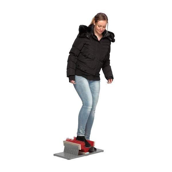 Eine Person benutzt einen Stiefelreiniger mit Metallbodenplatte und Bürsten zum Reinigen der Schuhe.