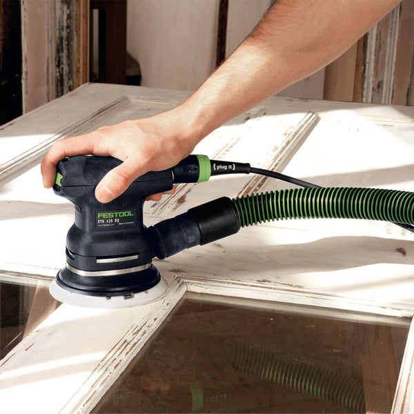 Eine Person schleift mit einem Exzenterschleifer von Festool eine Holztür.