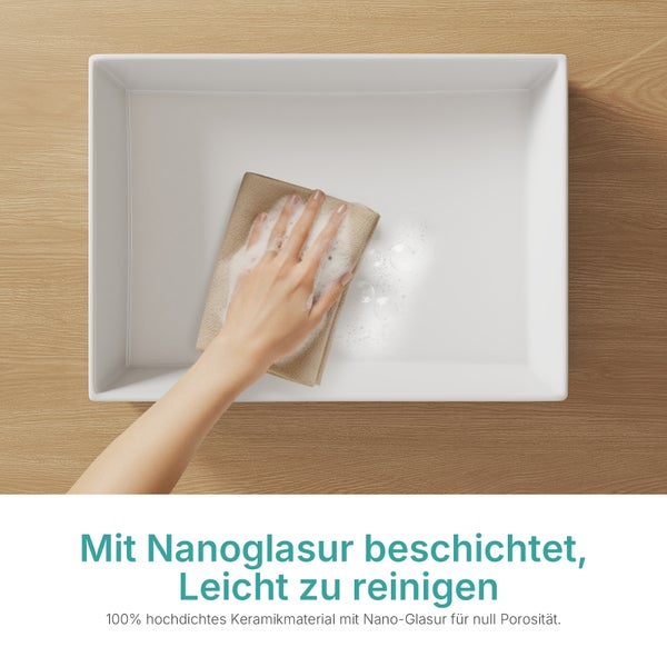 Hand reinigt ein rechteckiges Keramikwaschbecken mit einem Tuch und Seife. Das Becken hat eine Nanoglasur für einfache Reinigung.