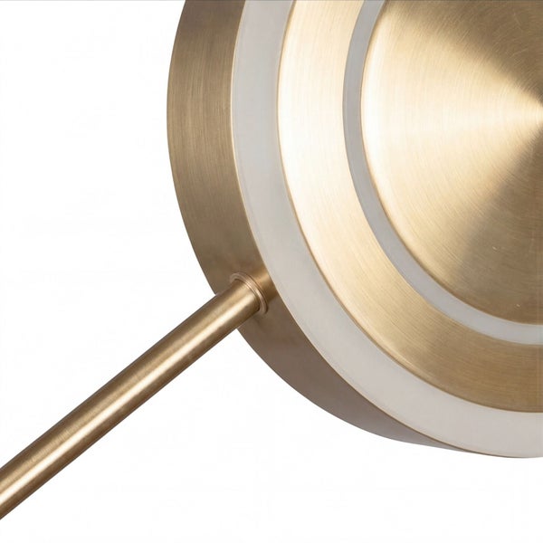 Detailansicht eines runden messingfarbenen Lampenkopfes mit weißen Leuchtringen und einem Metallstab.