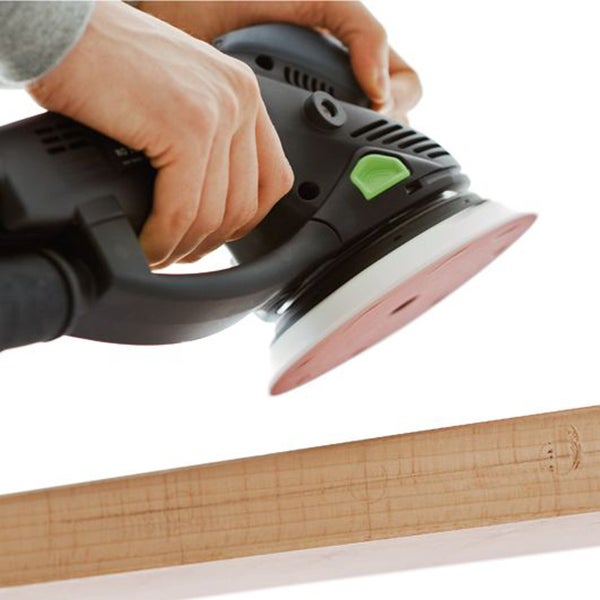 Eine Person schleift ein Holzbrett mit einem Exzenterschleifer.