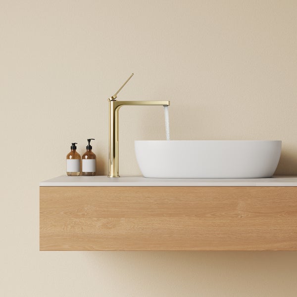 Modernes Badezimmer mit Waschtisch aus Holz und Aufsatzwaschbecken sowie goldener Waschtischarmatur mit fließendem Wasser.