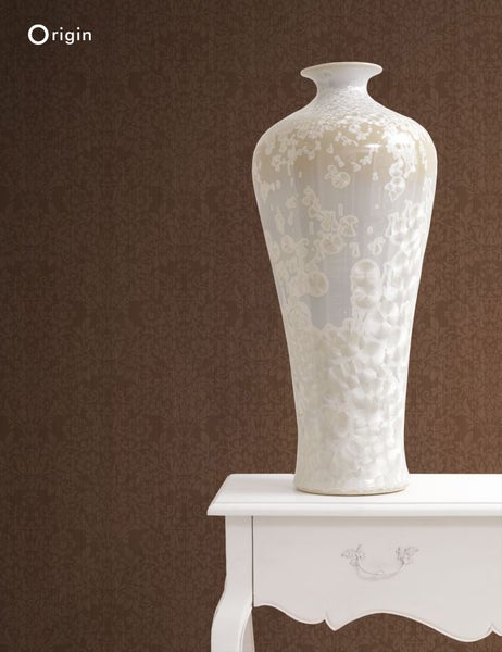 Dekorative Vase auf einem weißen Beistelltisch vor einer gemusterten Tapete