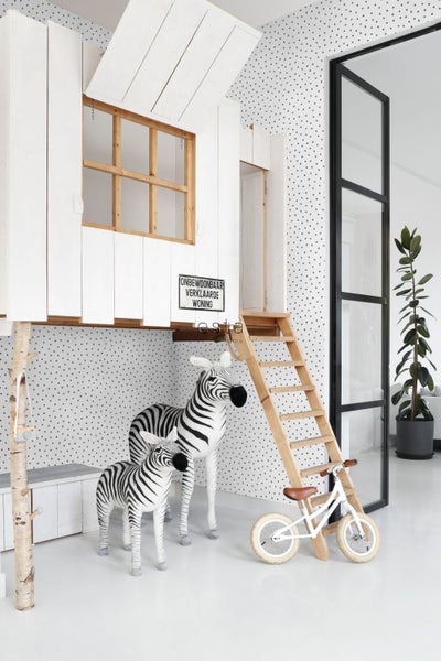 Dekoratives Kinderzimmer mit Spielhaus, Zebrafiguren und Laufrad