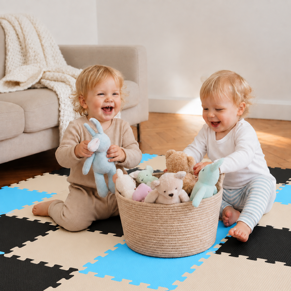 Zwei Kleinkinder spielen auf einer zusammengesetzten Puzzlematte aus Schaumstoff mit einem Korb voller Stofftiere in einem hellen Wohnzimmer.